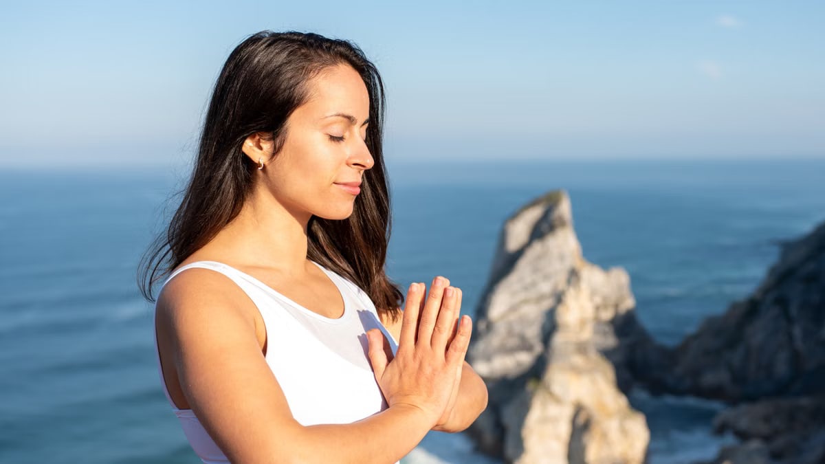 A woman meditates peacefully by the ocean in Portugal, embracing wellness.